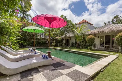 a house with a pool and a pink umbrella and a tub at Villa Sarah 4 chambres près de la plage Oberoi Seminyak in Seminyak