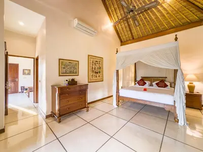 a bedroom with a canopy bed and a wooden dresser at Arjuna Villa 3 Bedroom Villa Seminyak in Seminyak