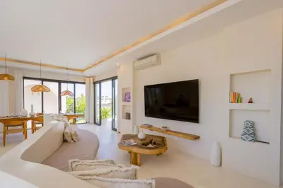a living room with a white couch and a tv at Sunset room in a shared 4 bedroom villa in Canggu