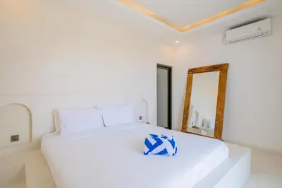 a white bedroom with a white bed and a mirror at Sunset room in a shared 4 bedroom villa in Canggu