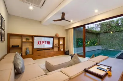 a living room with a tv and a swimming pool at Annora Cozy 3 BR Private Pool Villa in Canggu