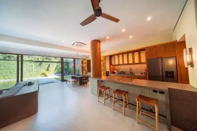 a kitchen with a bar with stools and a table at Annora Cozy 3 BR Private Pool Villa in Canggu
