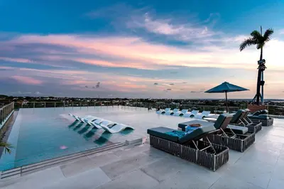 a large swimming pool with chairs and an umbrella at The Umalas Signature in Canggu