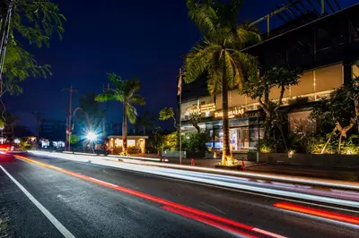 a city street with a building and palm trees at night at The Umalas Signature in Canggu