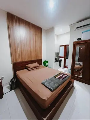 a bedroom with a large bed with a wooden headboard at Room Close to Seminyak - Cozy & Strategic Stay in Seminyak