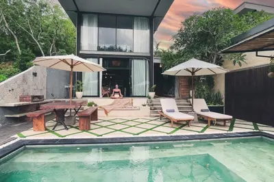 a house with a pool with a table and chairs at The Valley Loft in Ngurah Rai International Airport