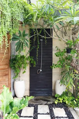 a black shower in a room with plants at The Valley Loft in Ngurah Rai International Airport