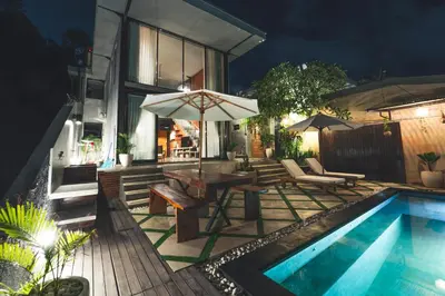 a patio with a table and an umbrella next to a pool at The Valley Loft in Ngurah Rai International Airport