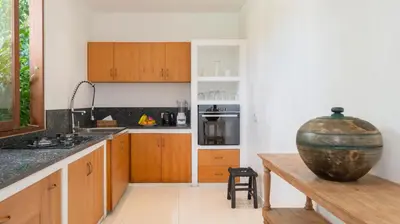 a kitchen with wooden cabinets and a large vase at Alea Estate by Villa Finder in Kerobokan