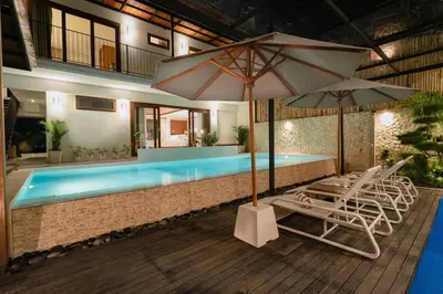 a swimming pool with lounge chairs and umbrellas at Luxury 4BR Private Pool Villa, Serene Lux Jimbaran in Jimbaran