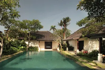 a swimming pool in front of a house at Taman Estate by Ekosistem in Seminyak