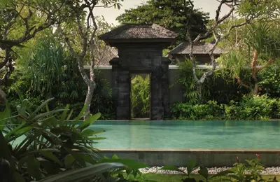 a swimming pool in the middle of a garden at Taman Estate by Ekosistem in Seminyak