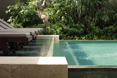 a swimming pool with benches next to a resort at Taman Estate by Ekosistem in Seminyak