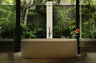 a bath tub in a room with plants at Taman Estate by Ekosistem in Seminyak
