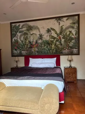 a bedroom with two beds and a painting on the wall at Casa Sophia by Kayana in Sanur