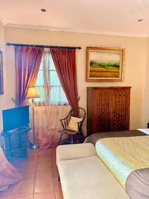 a bedroom with a bed and a desk and a window at Casa Sophia by Kayana in Sanur