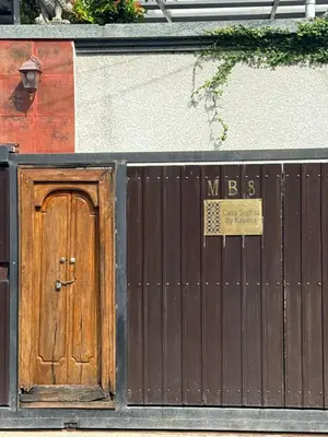 a wooden door with a sign on it next to a fence at Casa Sophia by Kayana in Sanur