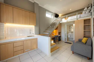 a kitchen with a staircase and a living room at Cove Nuansa Home in Jimbaran