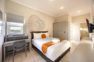 a bedroom with a bed and a desk and a window at Cove Nuansa Home in Jimbaran