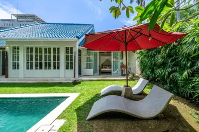 a house with a pool and a red umbrella at The Oasis Villa in Kerobokan