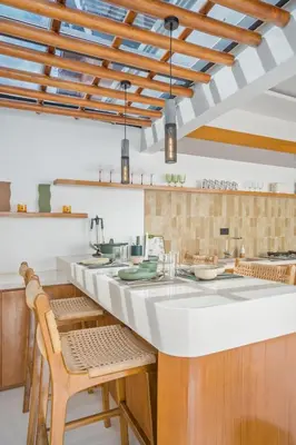 a kitchen with a large white counter and chairs at Rosso Verde 2BR Villa near Seminyak in Seminyak
