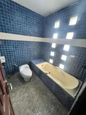 a blue tiled bathroom with a toilet and a tub at The Fatul Villa in Ngurah Rai International Airport