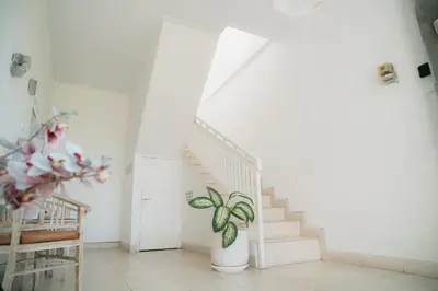 a white staircase with a plant in a room at Adijaya Room 1 in Seminyak