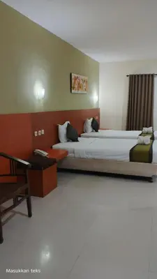 a hotel room with two beds and a desk at Puri dibia apartment in Kuta