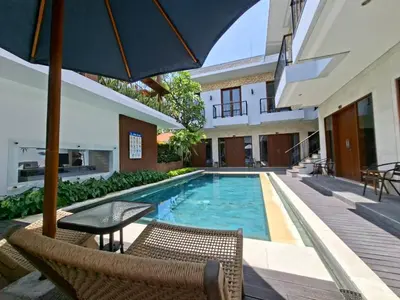 a swimming pool with a table and chairs and an umbrella at Mahesa Seminyak in Seminyak