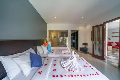 a bedroom with a large white bed with red flowers on it at Villa Sun Seminyak in Seminyak