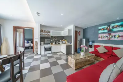 a living room with a red couch and a kitchen at Villa Sun Seminyak in Seminyak