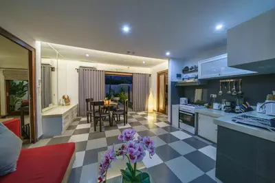 a kitchen and living room with a table with purple flowers at Villa Sun Seminyak in Seminyak