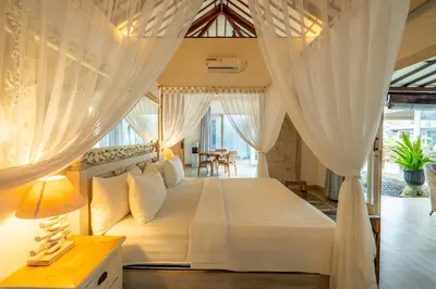 a bedroom with a large bed with white curtains at Luxury Aliya Villa by Betterplace in Sanur
