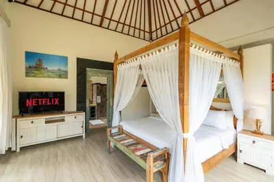 a bedroom with a four poster bed and a television at Luxury Aliya Villa by Betterplace in Sanur