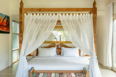 a bedroom with a canopy bed with white curtains at Luxury Aliya Villa by Betterplace in Sanur