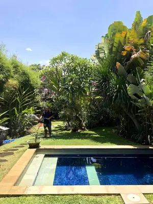 a man is standing next to a swimming pool at Lush 1 BR Private Pool Villa inSeminyak in Kerobokan