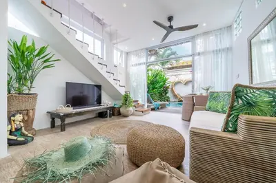 a living room with a couch and a tv at Villa 888 Tropical Heart - 1BR Pool Villa Seminyak in Seminyak
