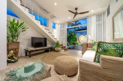 a living room with a couch and a tv at Villa 888 Tropical Heart - 1BR Pool Villa Seminyak in Seminyak