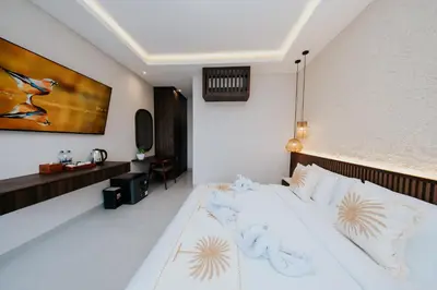 a bedroom with a large white bed and a desk at Casa Nika Suites Seminyak in Seminyak