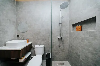 a bathroom with a shower and a toilet and a sink at Casa Nika Suites Seminyak in Seminyak