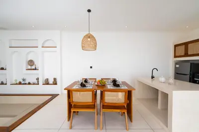 a kitchen with a wooden table and some chairs at Villa Bellora by Pertama Management in Seminyak