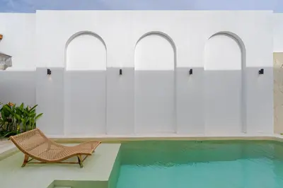 a chair sitting next to a swimming pool at Villa Bellora by Pertama Management in Seminyak
