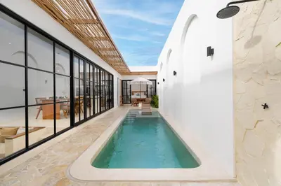 an indoor swimming pool in a house with glass windows at Villa Bellora by Pertama Management in Seminyak