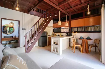 an open kitchen and living room with a staircase at Pura Villa in Uluwatu in Jimbaran