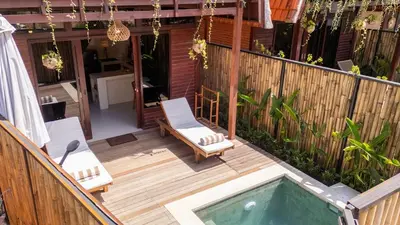 a patio with two chairs and a swimming pool at Pura Villa in Uluwatu in Jimbaran