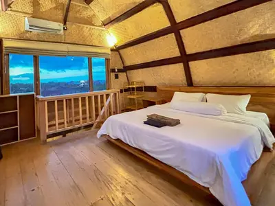 a bedroom with a bed and a large window at Makaha Bungalow in Jimbaran