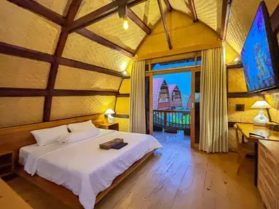 a bedroom with a bed and a large window at Makaha Bungalow in Jimbaran