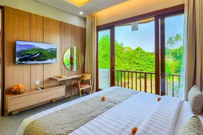a bedroom with a large bed and a balcony at Belisaria Comfortable 3 BR Private Pool Villa in Sanur