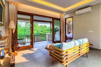 a living room with a couch and a balcony at Belisaria Comfortable 3 BR Private Pool Villa in Sanur