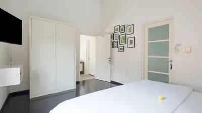 a white bedroom with a bed and a tv at Villa Merta Sari 8 by Villa Finder in Seminyak